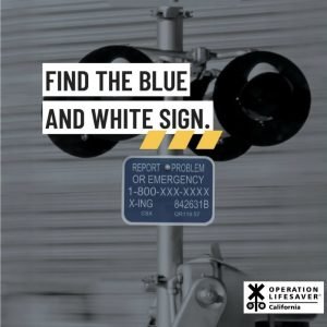 Blue and White Emergency Notification System sign located near railroad crossings